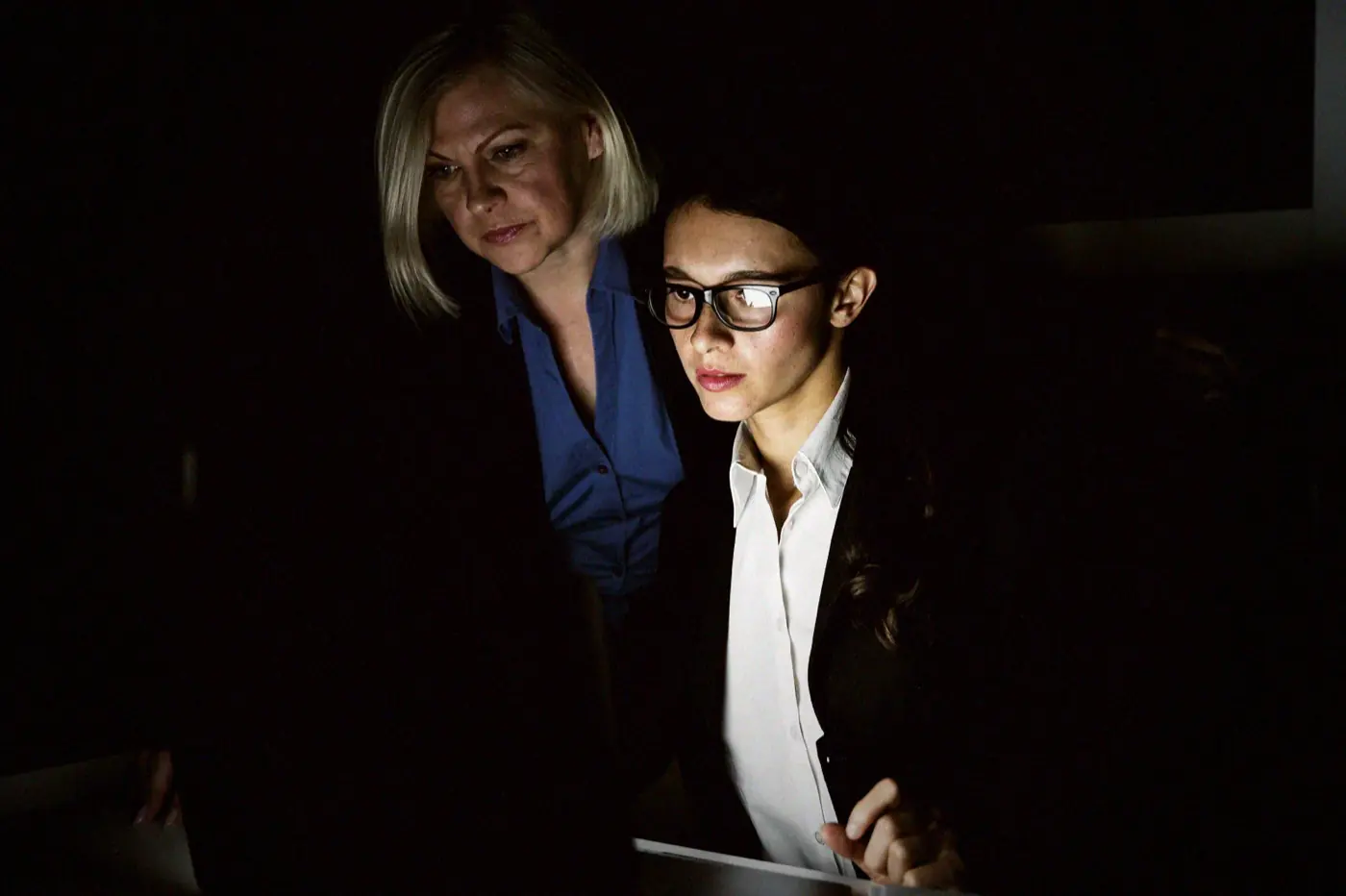 Two colleagues working late at a desk, the weekend shift that follows a second PHP advisory in one week.