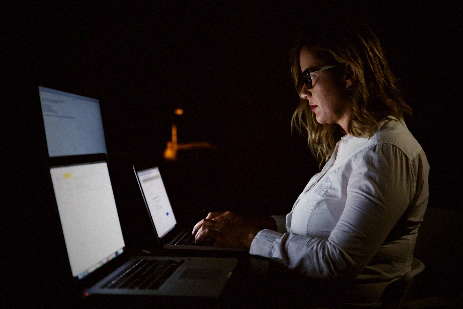 A business owner reviewing account access late at a lit laptop in a dark Manila office.