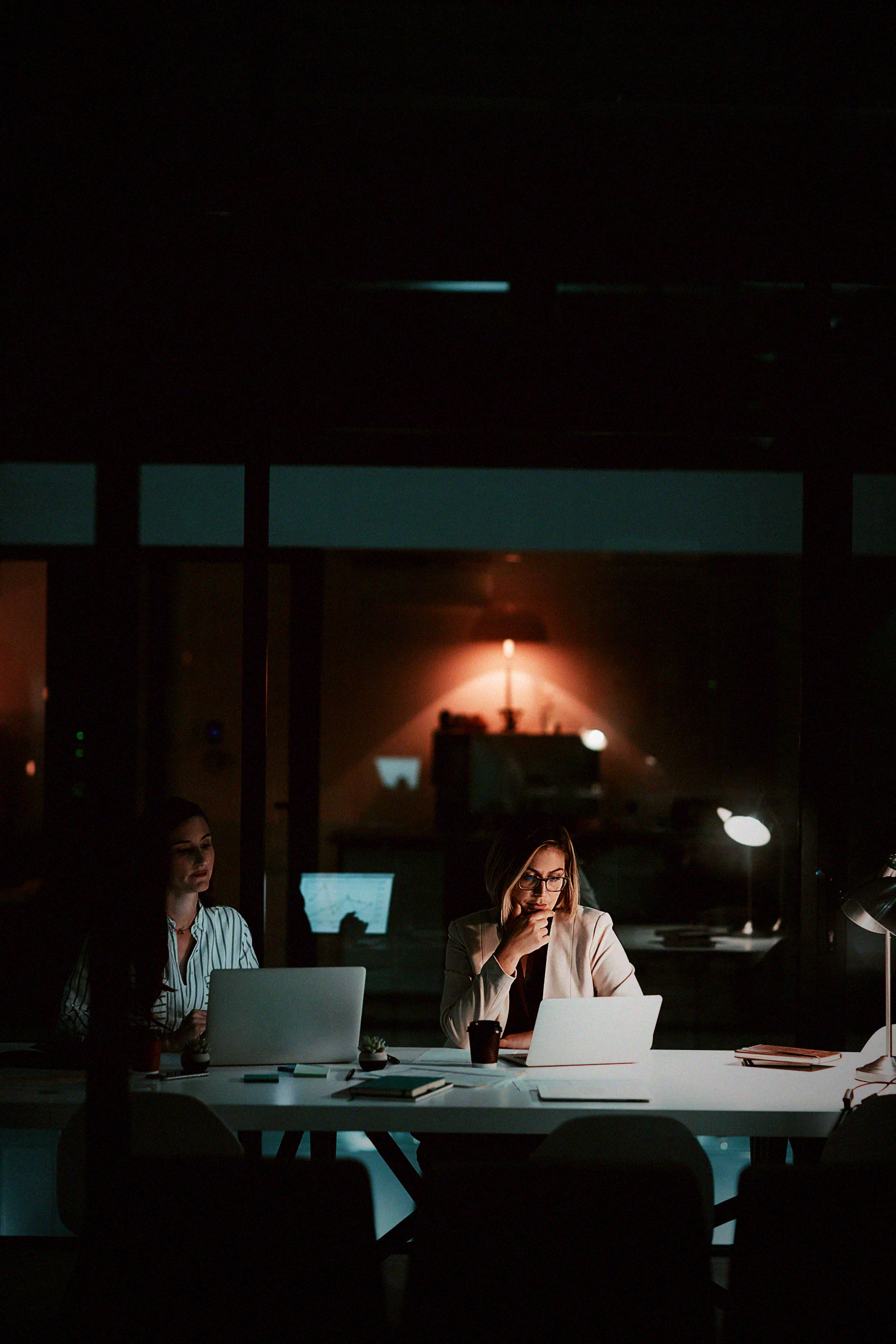 A lone employee at a laptop in a dark office at night, the quiet setting where retained access is used long after someone has left.